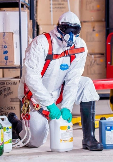 Odor removal technician in protective gear preparing treatment